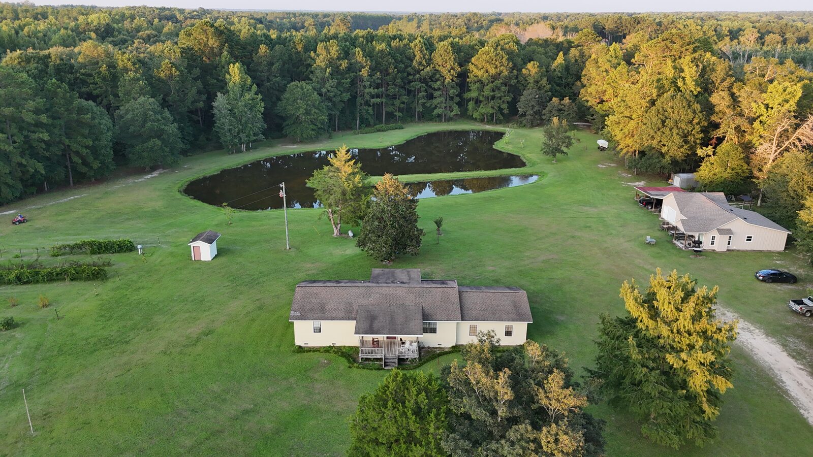 Aerial view of property with house, pond and outbuildings